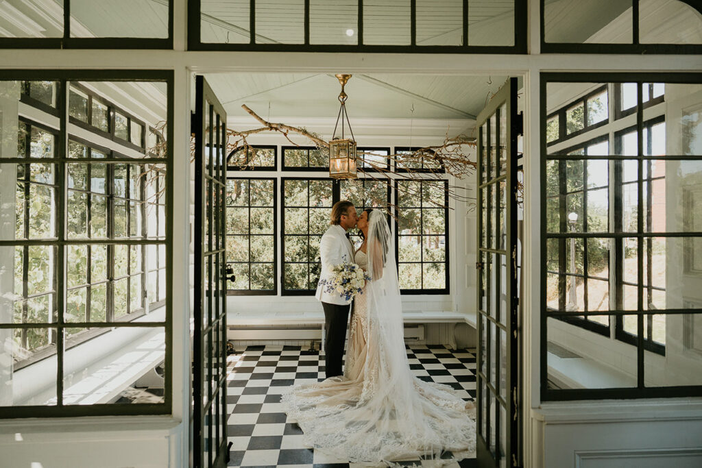 the bride and groom kissing in a sunroom. 