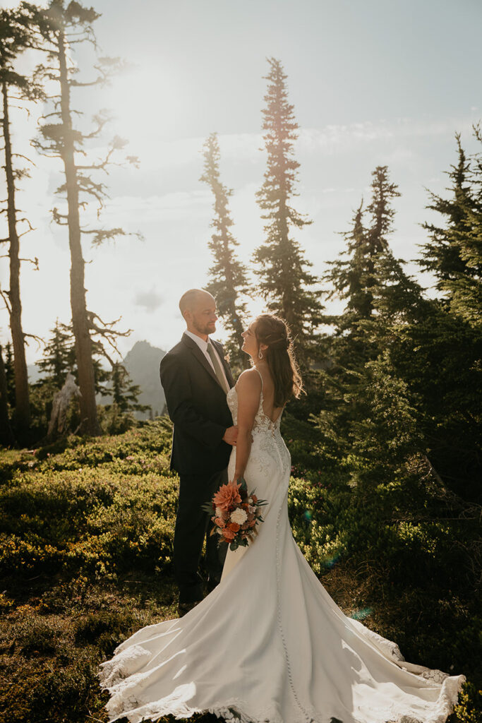 A couple looking lovingly at each other with trees in the background in Mt Rainier National Park. 