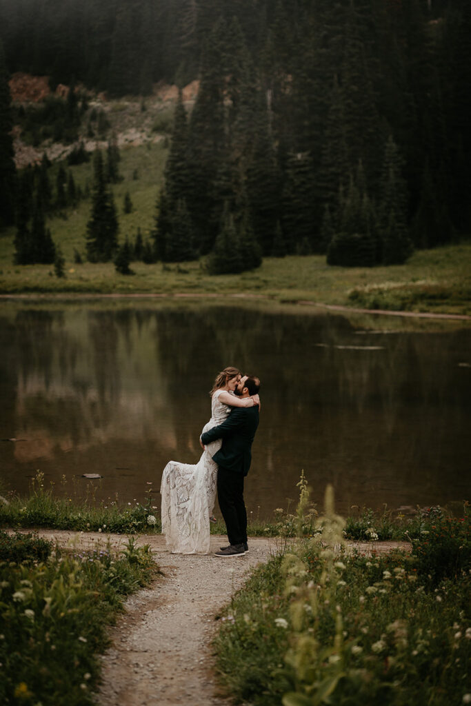 A couple kissing in front of a lake in Mt Rainier National Park. 