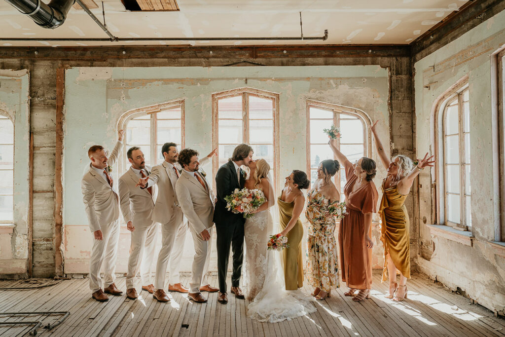 the bride and groom kissing surrounded by their wedding party at The Ruins at the Astor. 