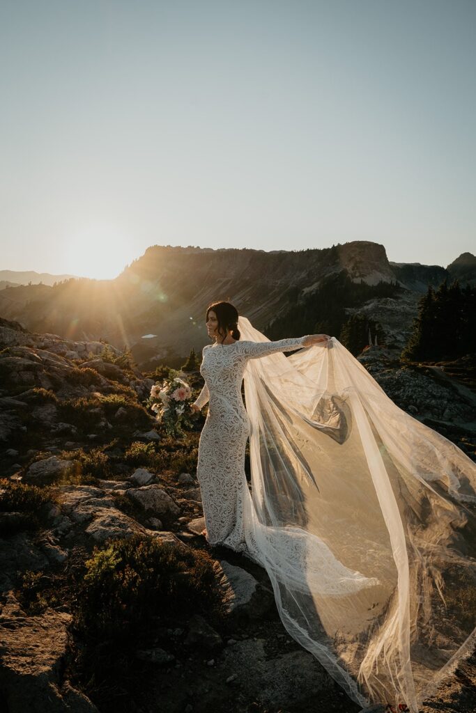 Brie holds her veil as it flutters in the wind at her elopement in the North Cascades