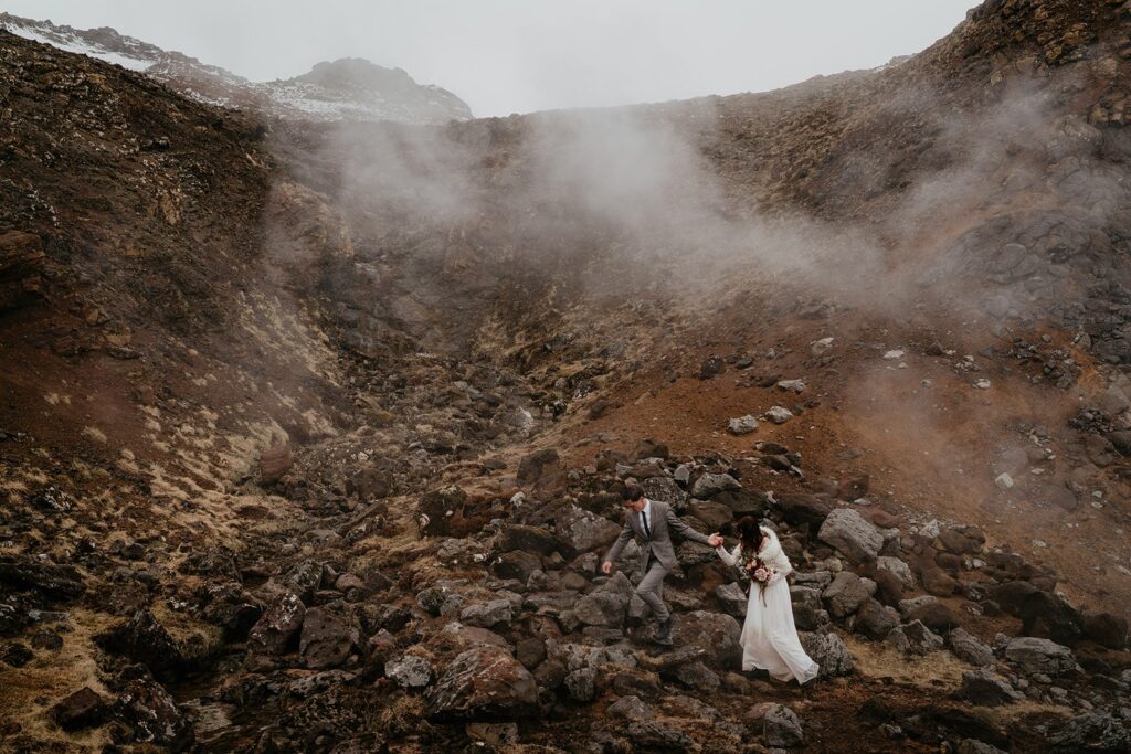 Bride and groom hold hands while walking across a hot springs at their Iceland elopement 