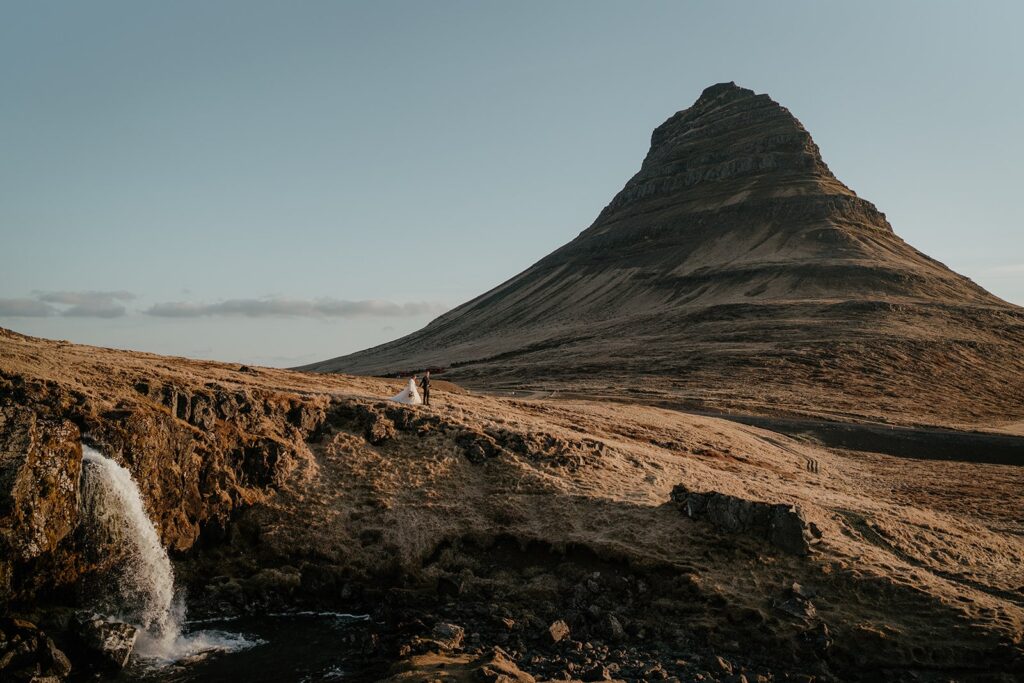 Bride and groom hold hands while walking around Kirkjufell during their elopement in Iceland