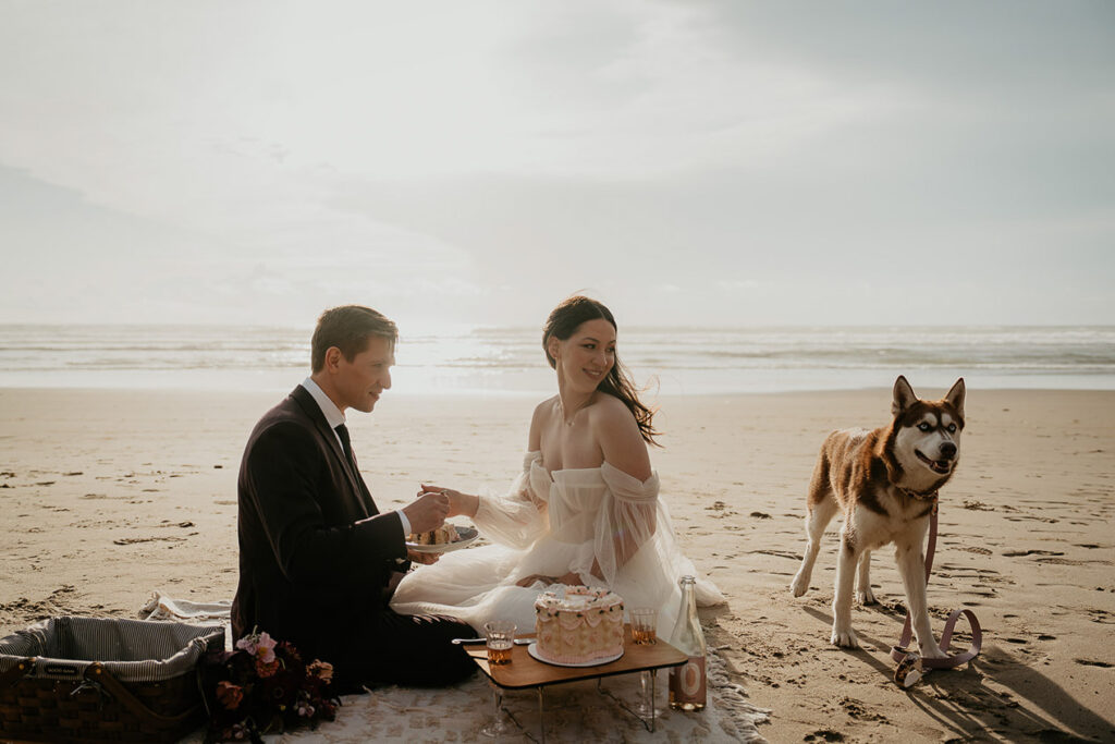 A couple having a picnic on the beach with their dog during their Oregon Coast elopement. 