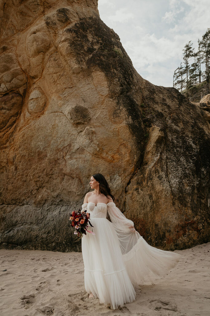 The bride posing in-front of a rock during her Oregon Coast elopement.