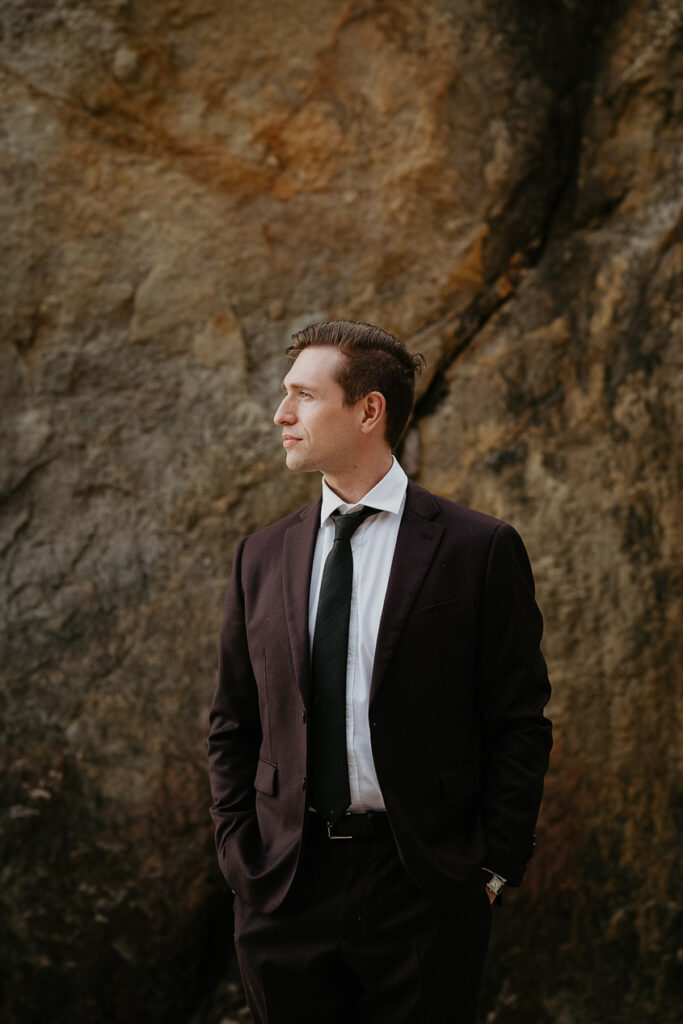 The husband posing in-front of a rock during her Oregon Coast elopement.