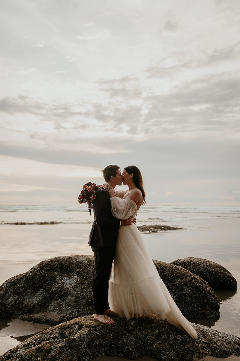 the newlyweds kissing with the ocean in the background during their Oregon Coast elopement.