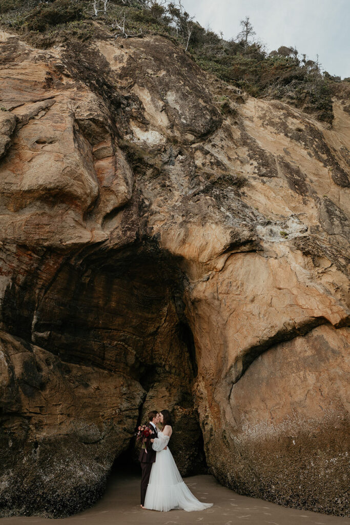 the newlyweds kissing next to the cliffside on the Oregon Coast.