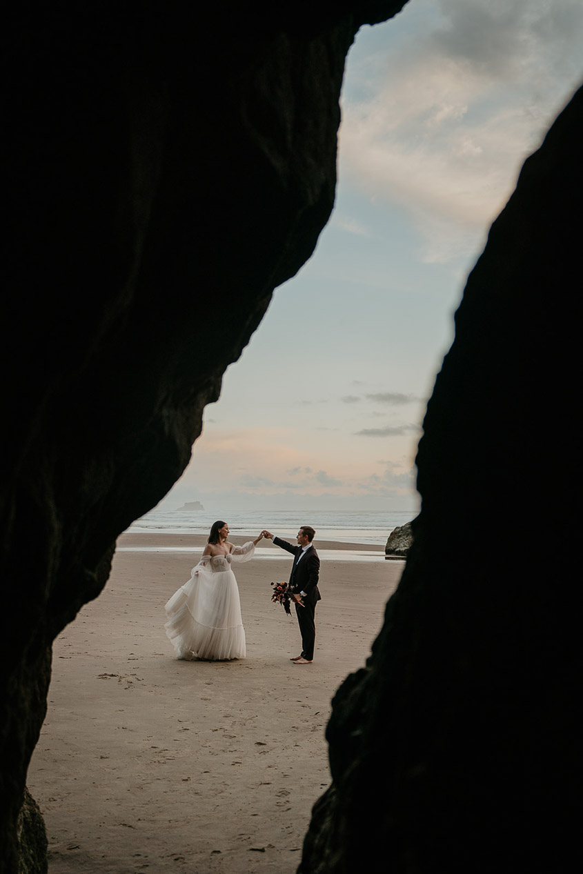 The newlyweds holding hands on the beach. 