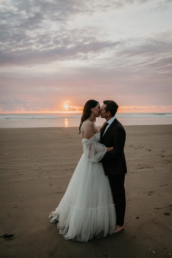 The newlyweds kissing during sunset on the Oregon Coast.