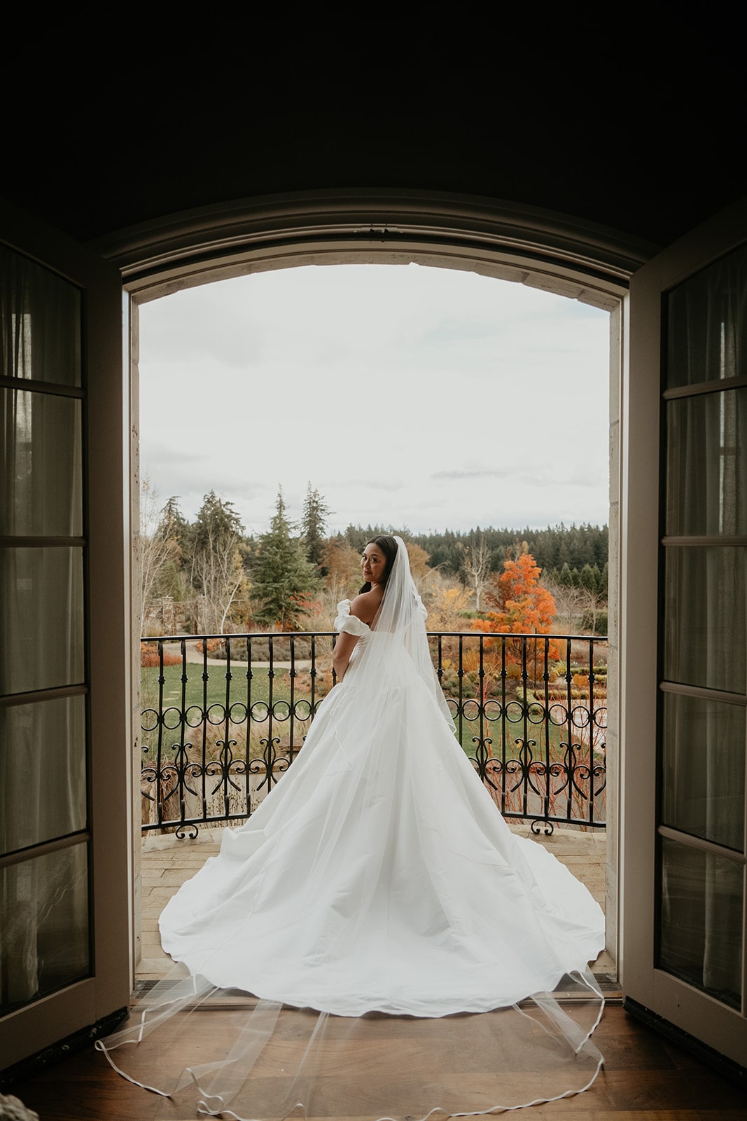 Bride stands on the upper patio overlooking the lawn at a chateau wedding venue in Oregon