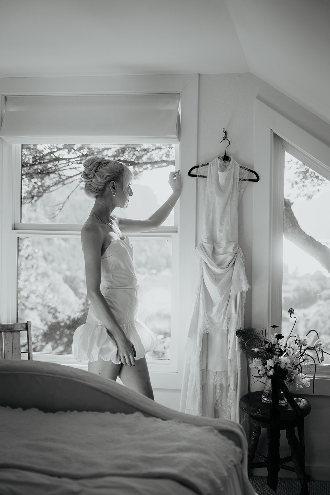 Bride reaches for a white wedding dress hanging from a hook at the Griffin House wedding venue in Oregon