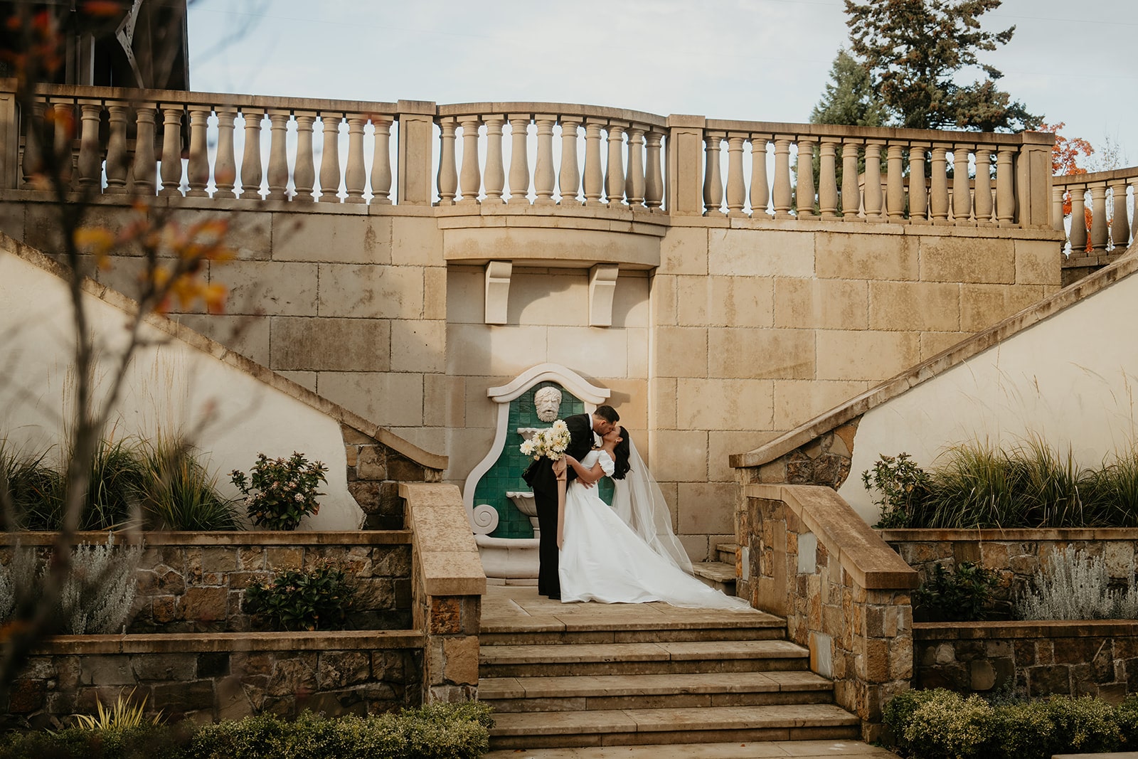 Bride and groom kiss on the steps of a chateau wedding venue