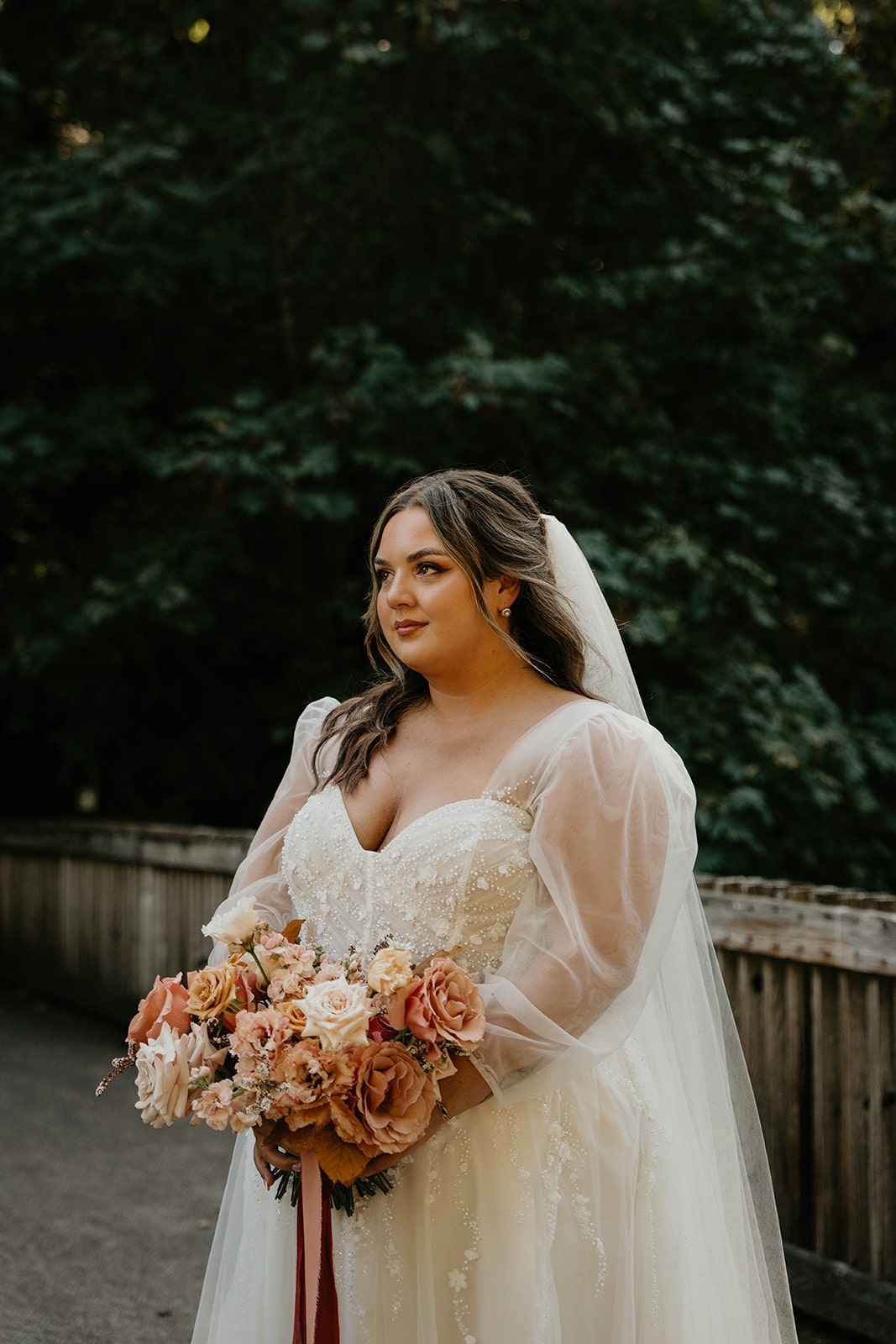 Bride holds a flower bouquet filled with cream and dusty rose colored florals