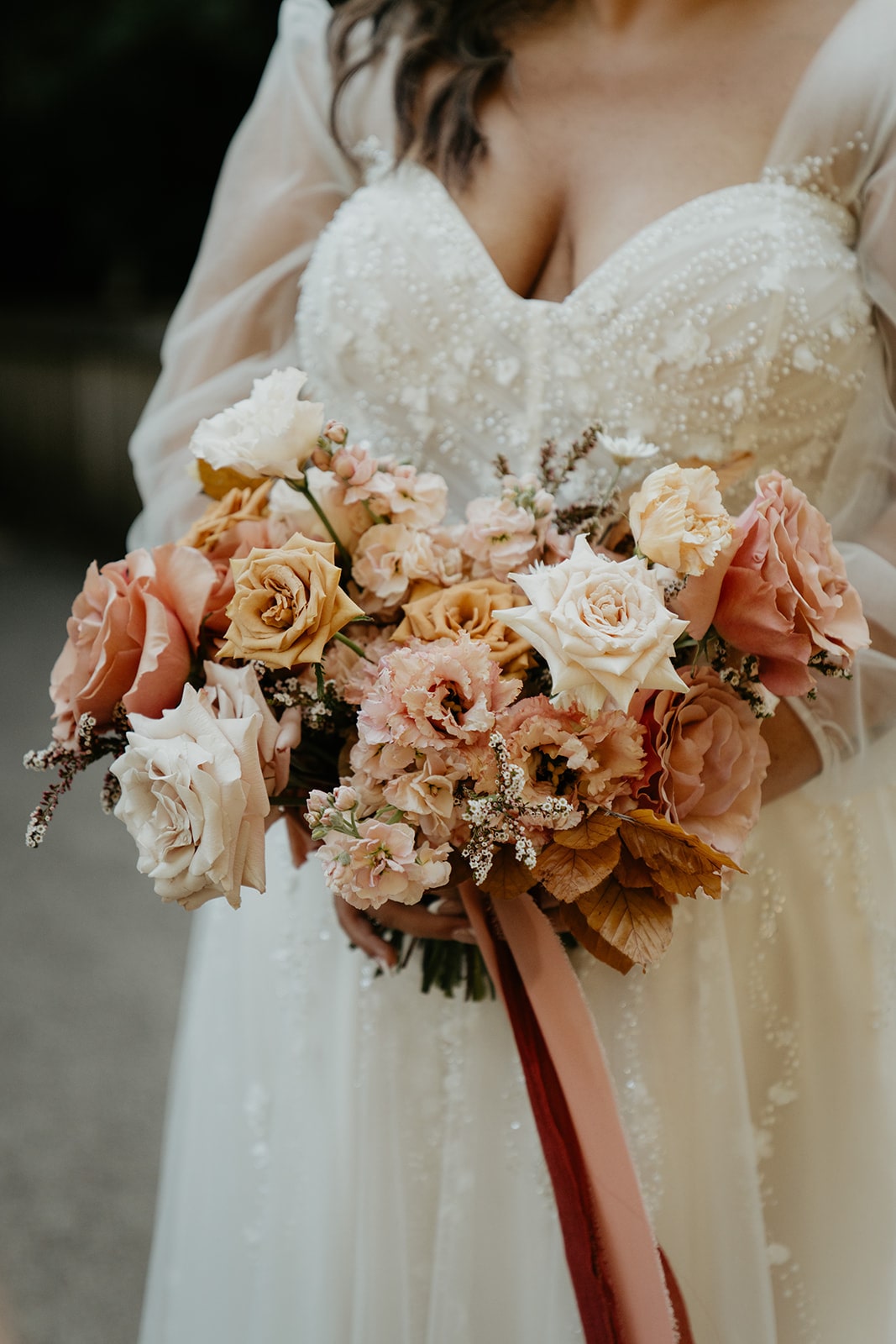 Bride holds a flower bouquet filled with cream and dusty rose colored florals