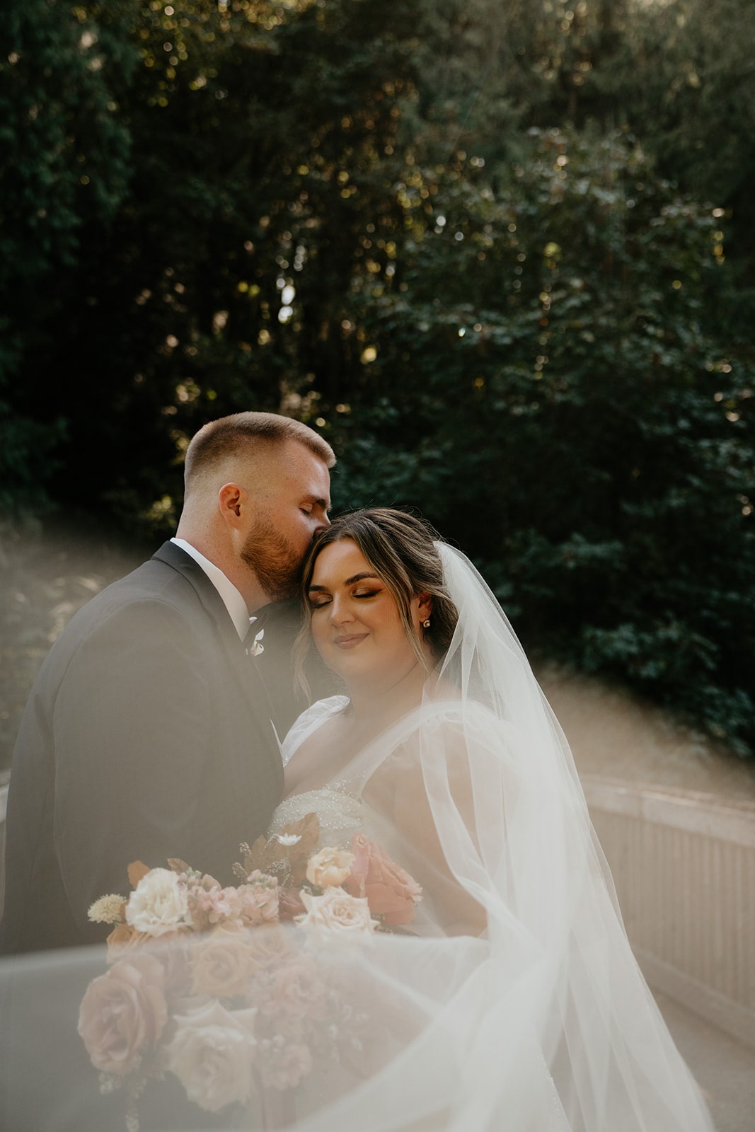 Groom kisses bride on the top of her head during their Ironlight Lake Oswego wedding photos 