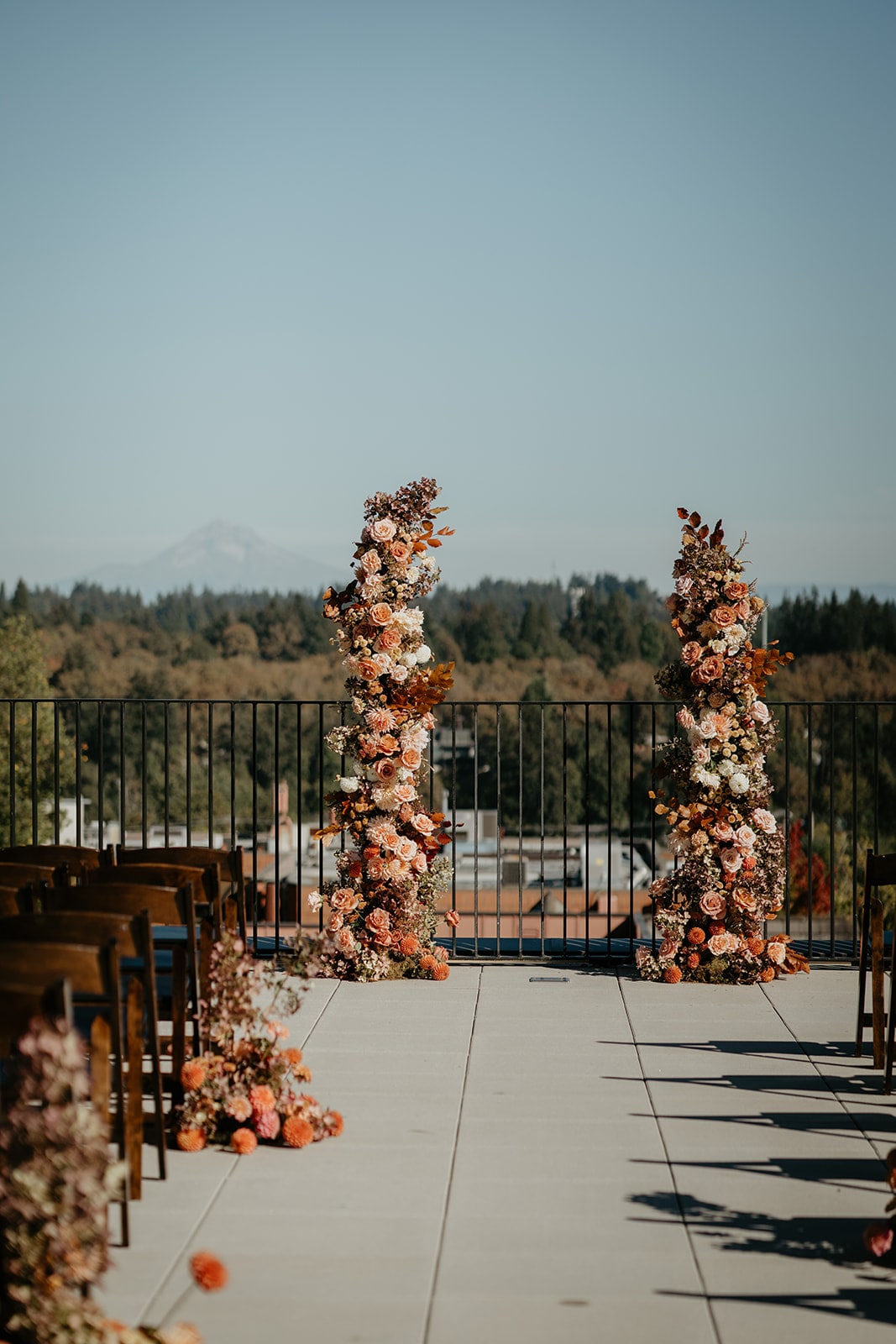 Orange, beige, and cream wedding flower arches on a rooftop at Ironlight wedding venue in Lake Oswego, Oregon