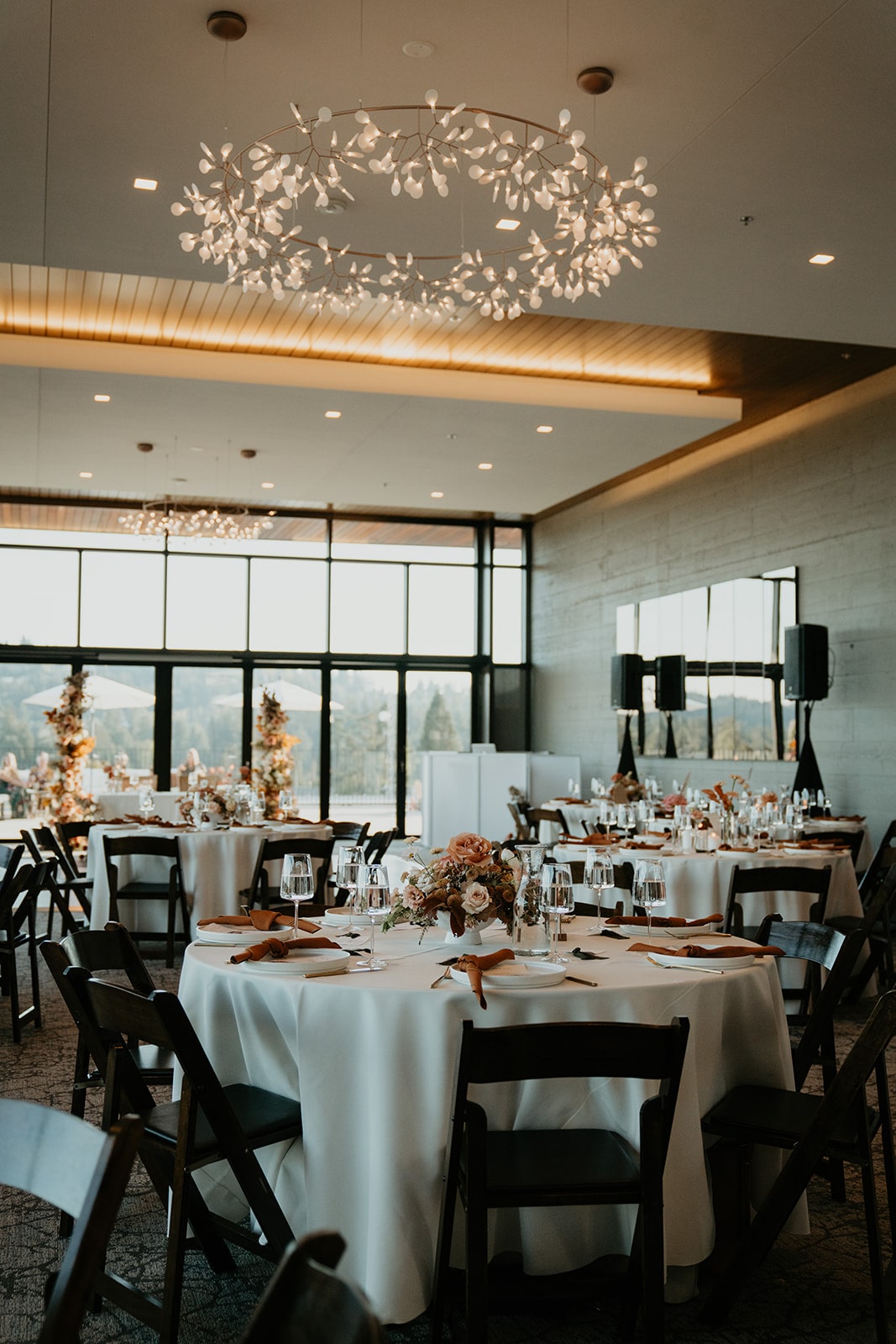 Round wedding reception tables decorated with orange and pale pink wedding flowers and napkins