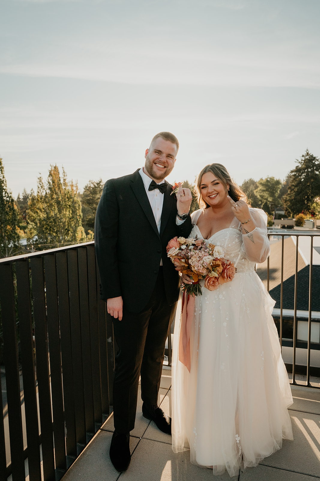 Bride and groom hold up their ring fingers during their sunset wedding photos at Ironlight Lake Oswego