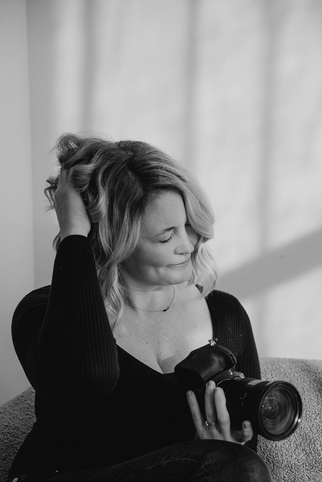 Oregon wedding photographer plays with her hair while holding a digital camera during her studio branding session