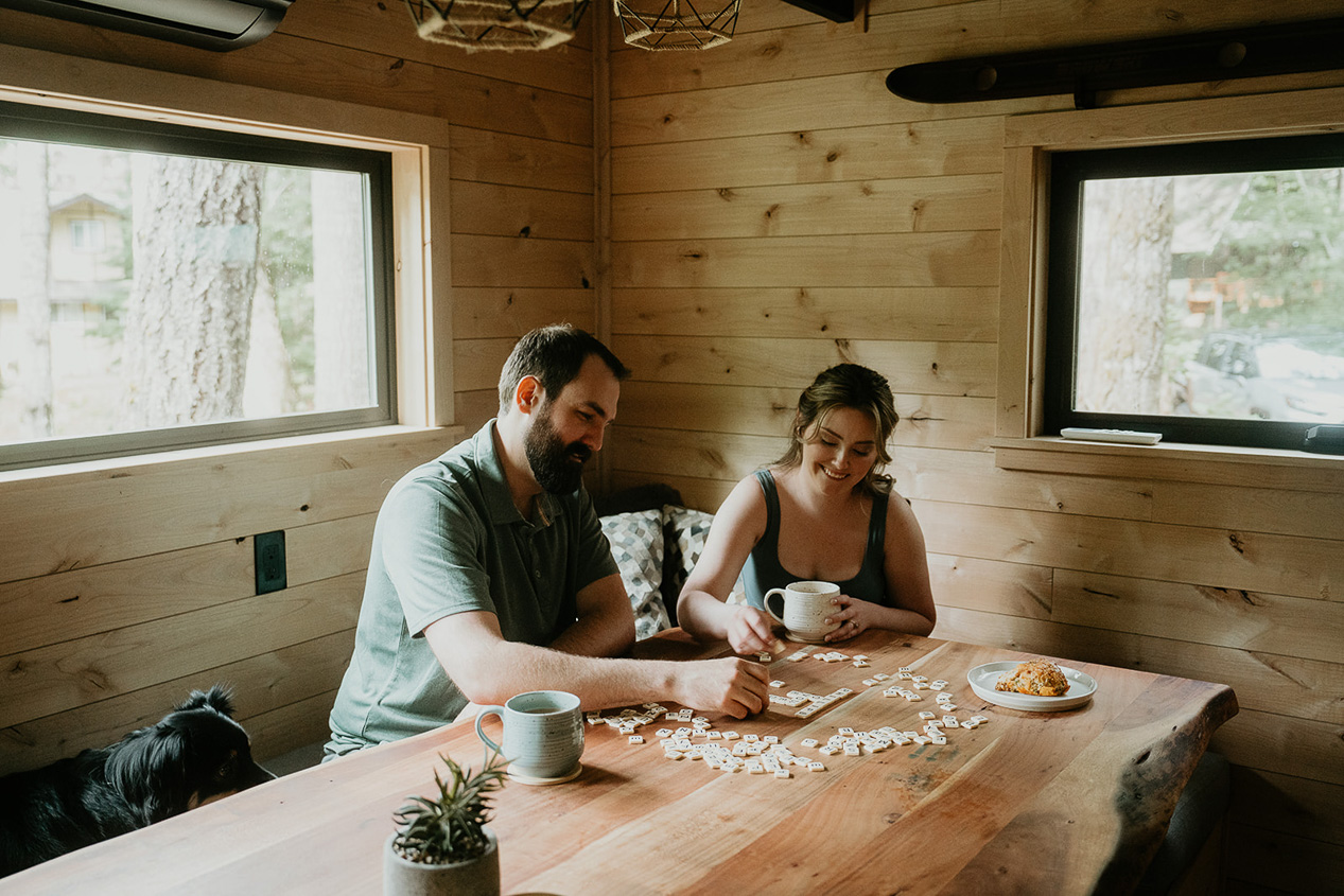 A couple playing Bananagrams in a cozy cabin, a fun an inexpensive activity when considering how much cost it is to elope.