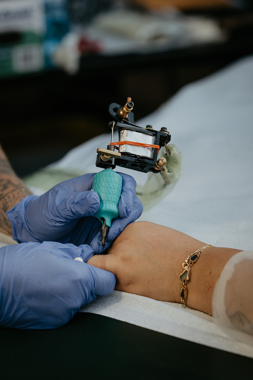 a tattoo artist tattooing a finger.