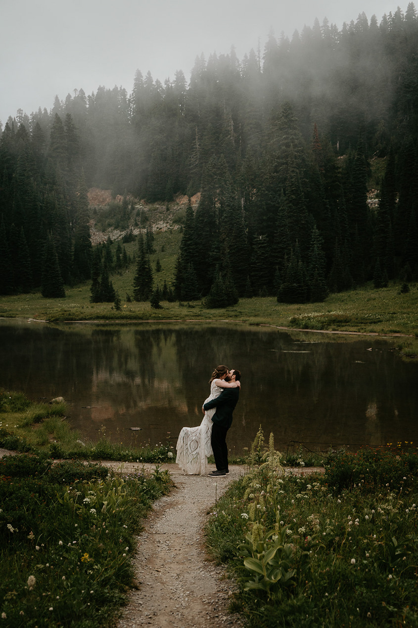 newlyweds kissing by a foggy lake, sweetened by how much more inexpensive the cost for them to elope versus have a traditional wedding is.