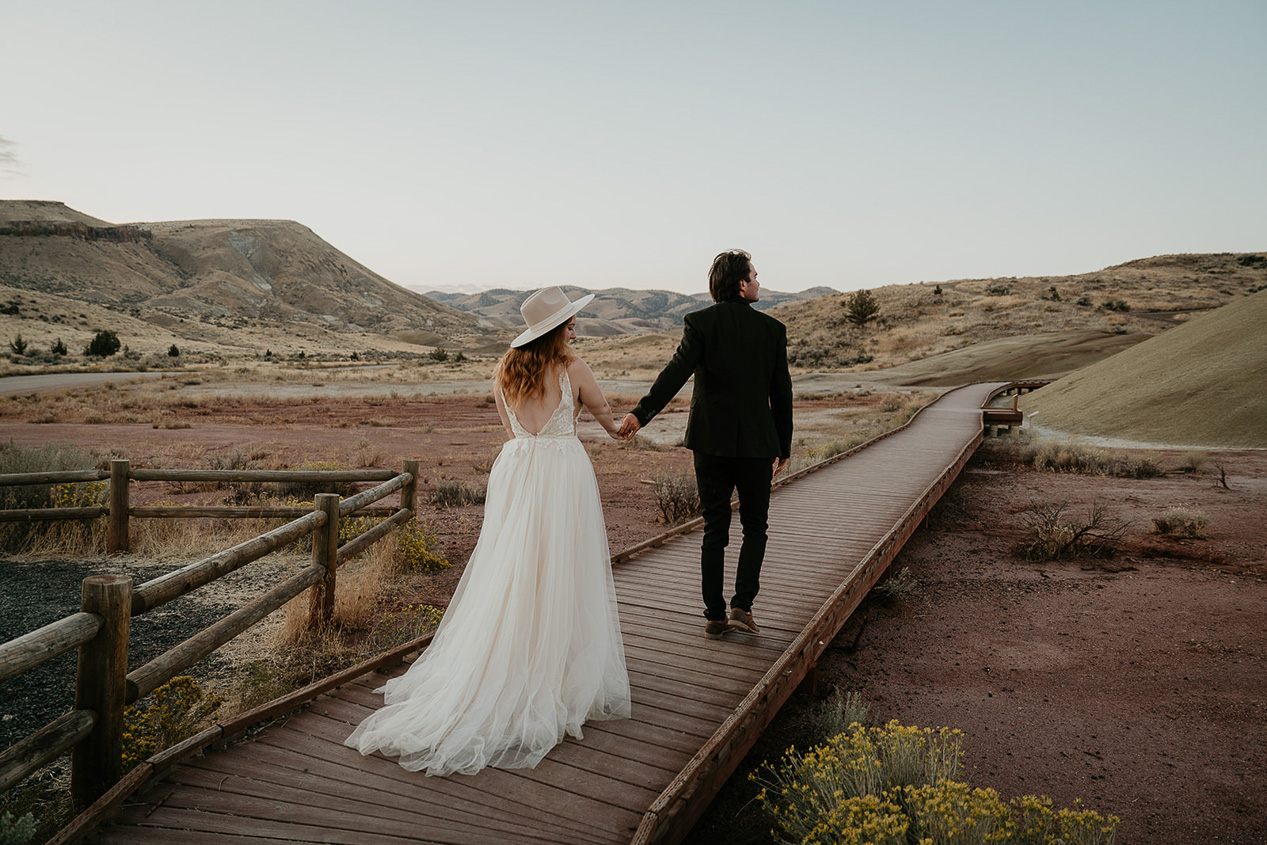 the groom leading the bride on a wooden bridge in Oregon.