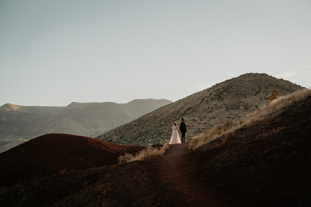 the newlyweds posing on a hiking trail during golden hour in Oregon at their painted hills elopement.