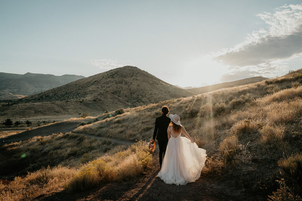 the newlyweds hiking on a trail in Painted Hills as the sun sets.