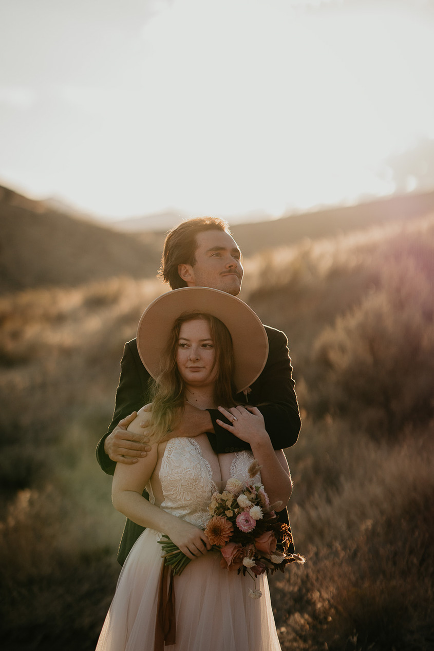 the newlyweds holding each other as the sun sets in the background.
