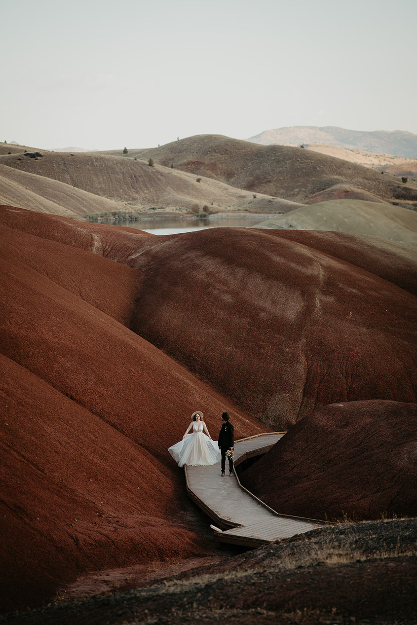 the newlyweds dancing on a boardwalk while hiking through painted hills during their elopement.