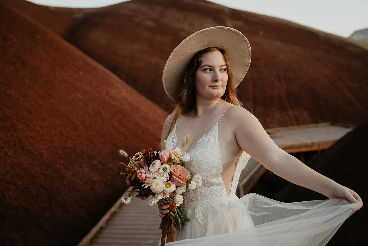 the bride showing off her dress with colorful hills in the background.