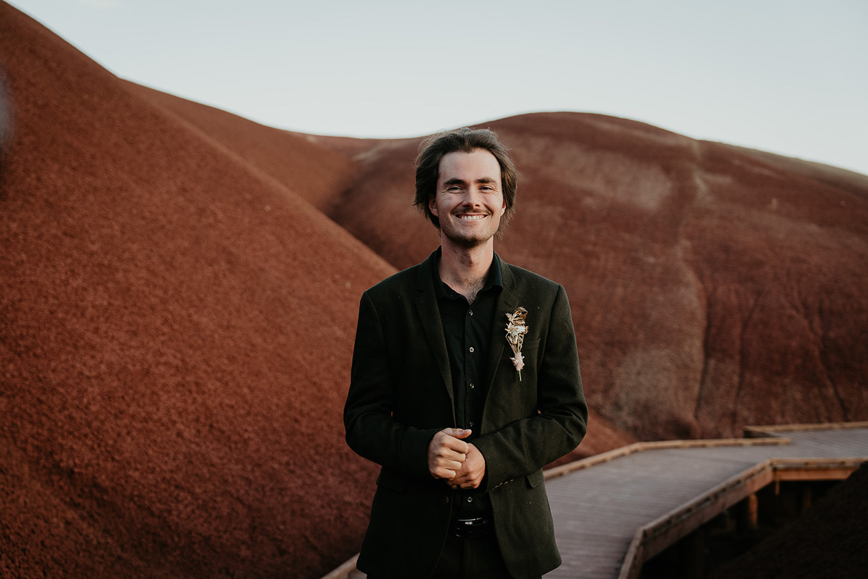 the groom smiling while standing on a boardwalk during his painted hills elopement.