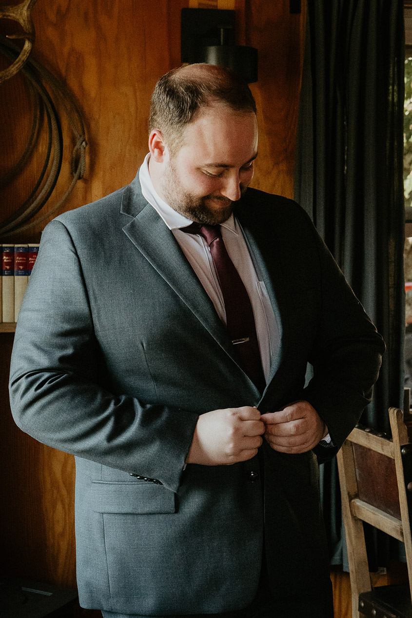 the groom adjusting his suit jacket during his wind mountain ranch wedding.