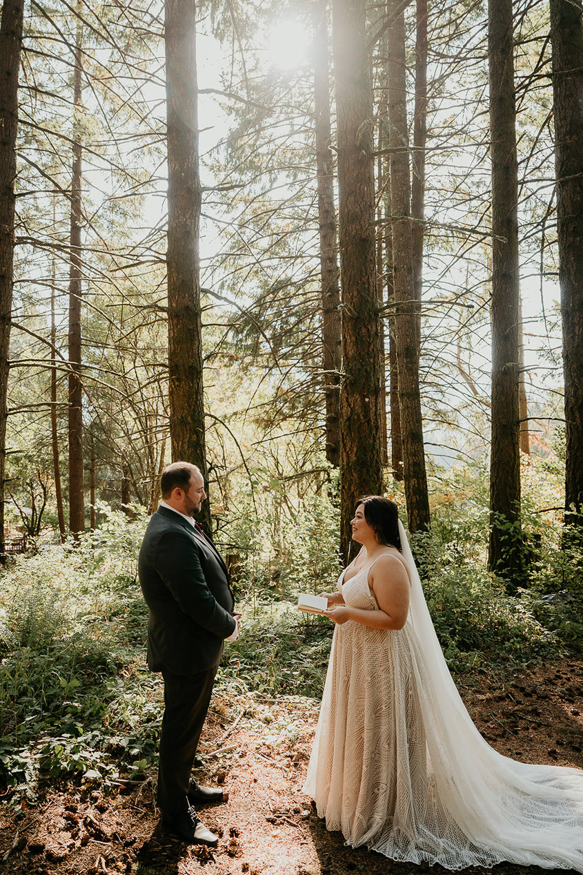 the newlyweds exchanging personal vows in the forest during their wind mountain ranch wedding.