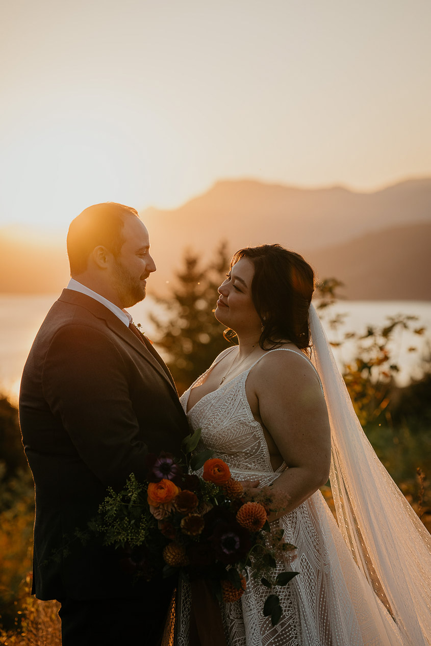 the newlyweds looking lovingly into each other's eyes at sunset during their wind mountain ranch wedding.