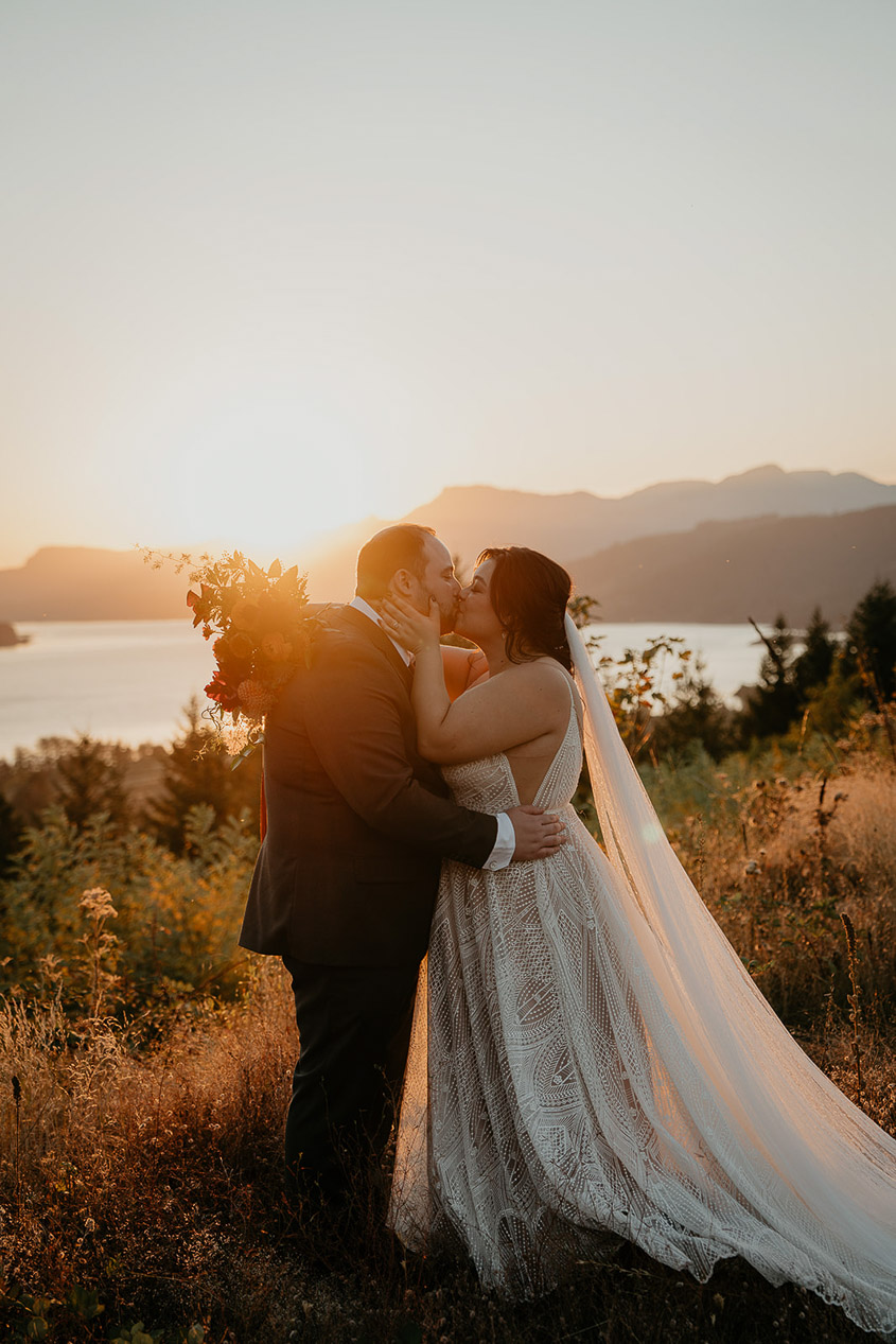 the newlyweds kissing at sunset during their wind mountain ranch wedding.