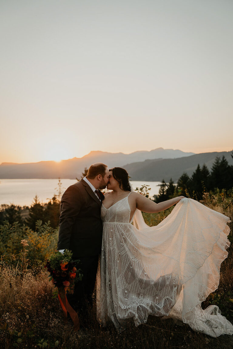 the newlyweds embracing each other at sunset during their wind mountain ranch wedding.