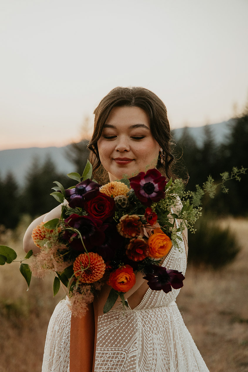 the bride posing with her colorful bouquet during her wind mountain ranch wedding.