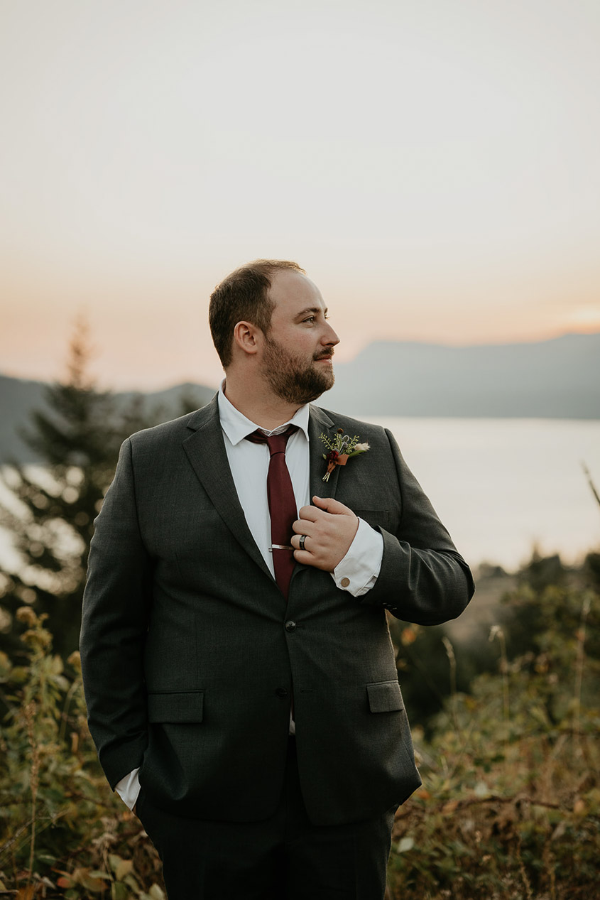 the groom holding his jacket and looking off into the distance during his wind mountain ranch wedding.
