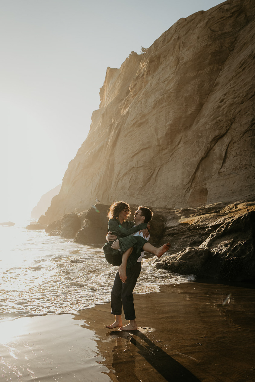 a couple dancing on the sand during their cape kiwanda engagement.