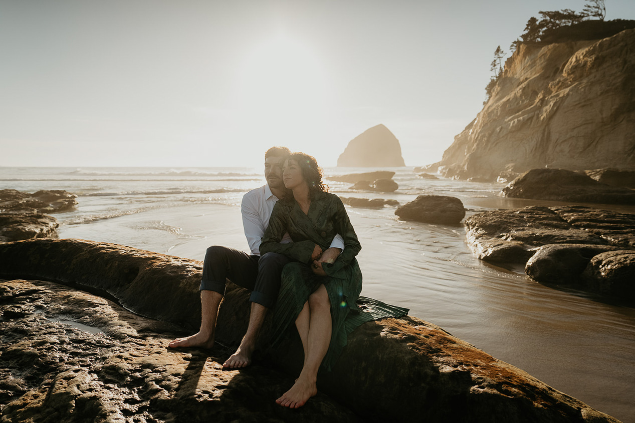 a couple hugging on a log during their cape kiwanda engagement.