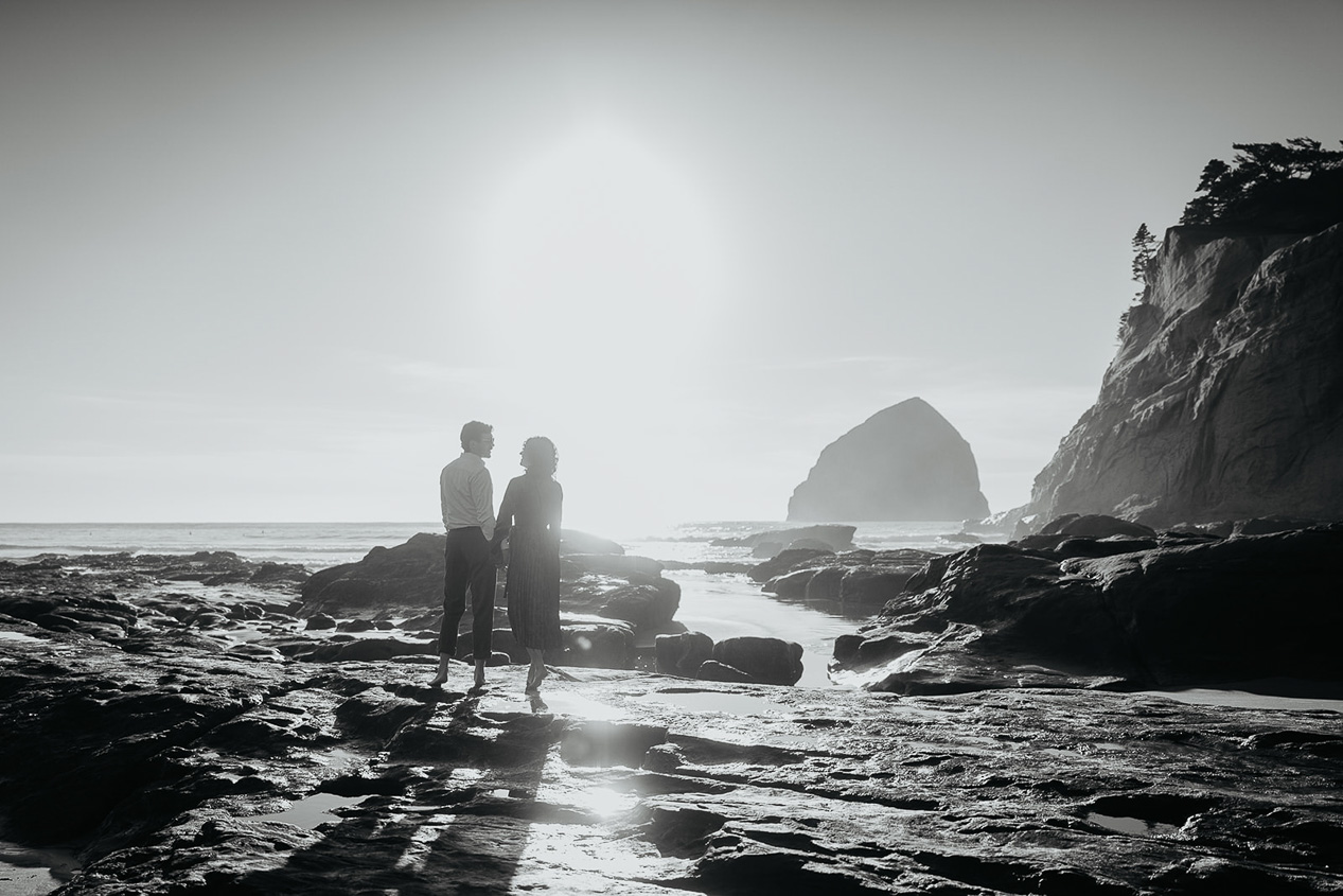 a couple holding hands walking on the Oregon coastline.