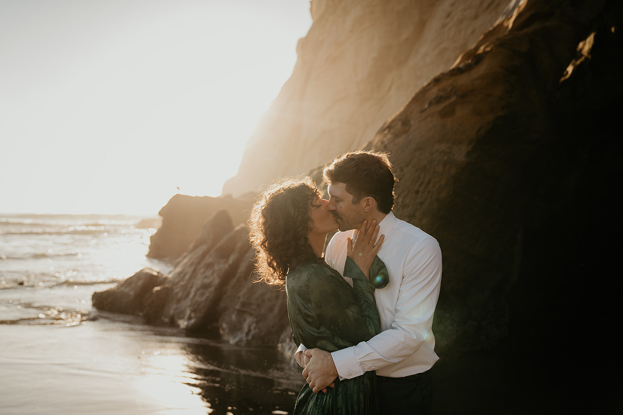 a couple kissing as the sun sets on the Oregon coastline.