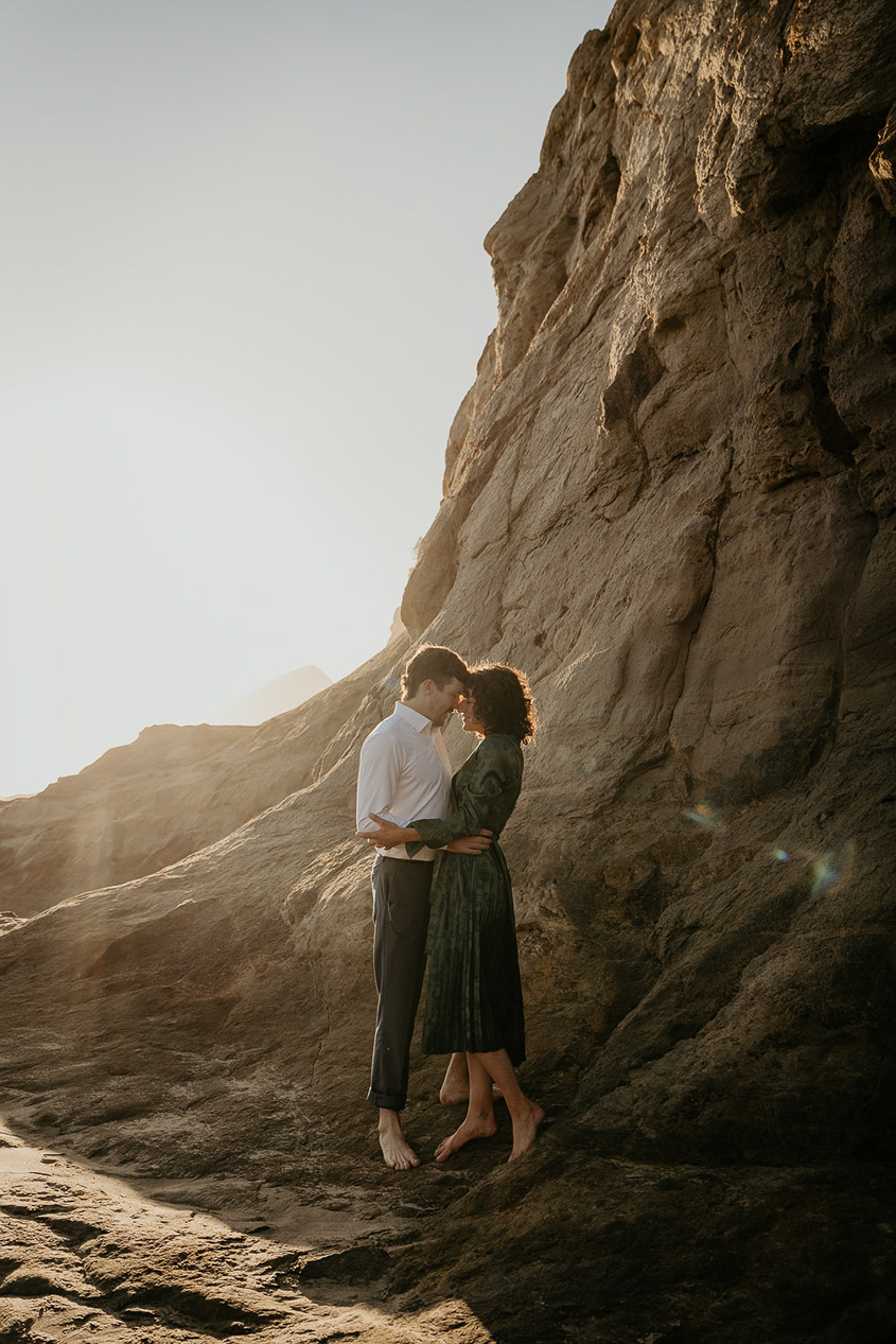 A couple holding each other near a cliff during their cape kiwanda engagement.