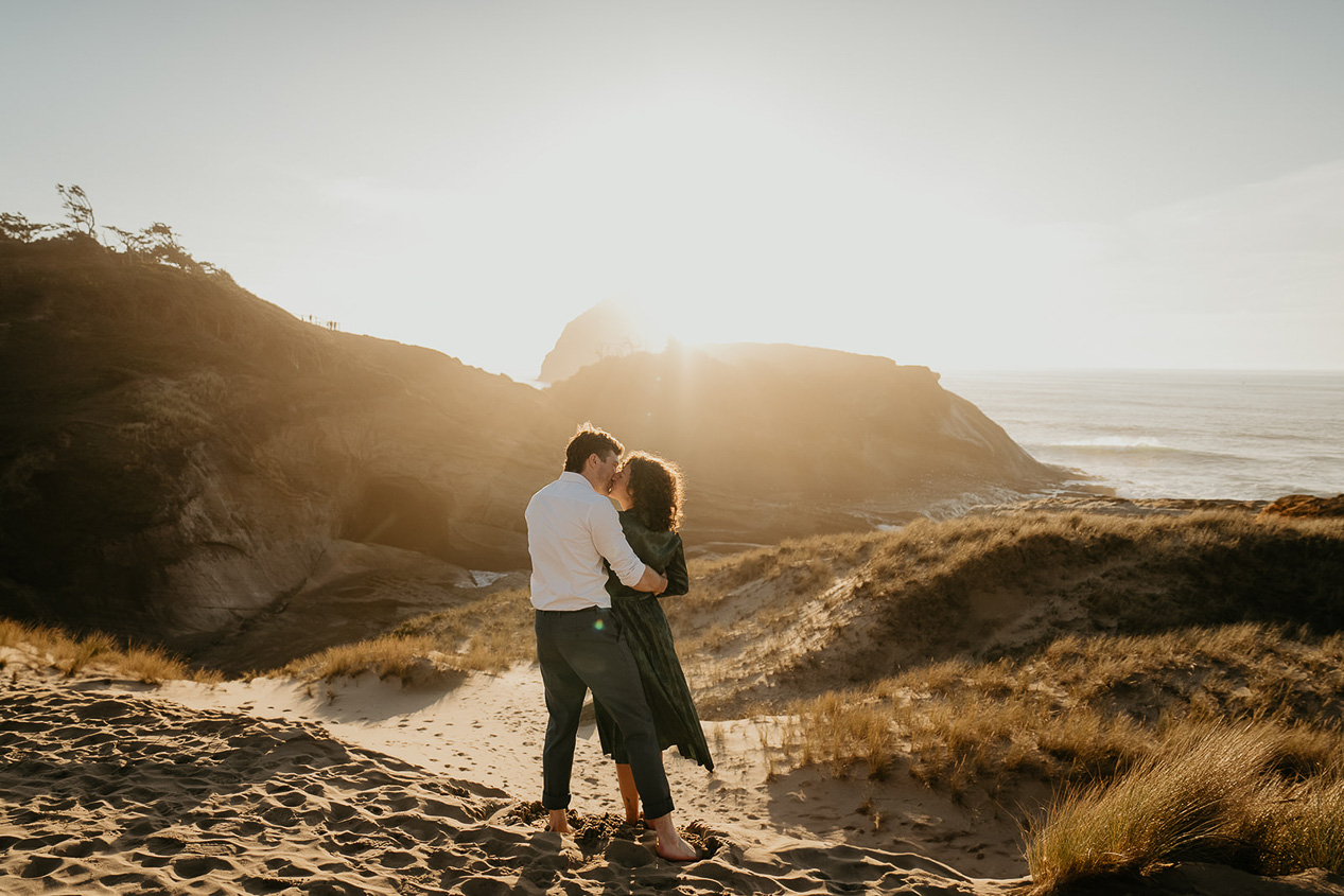 a couple kissing on a sandy beach during their cape kiwanda engagement.