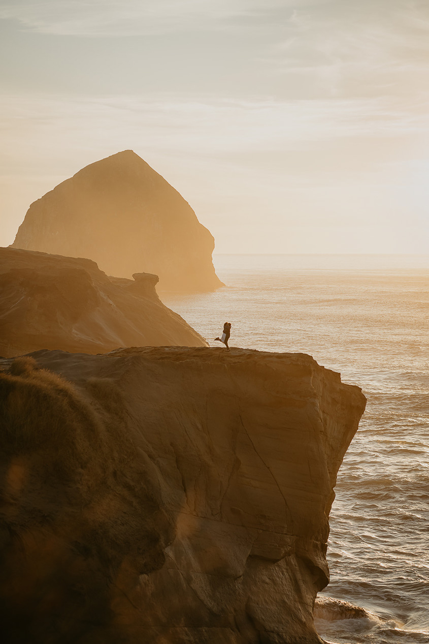 a couple dancing on a cliffside with the Oregon coast and a sea stack in the background.