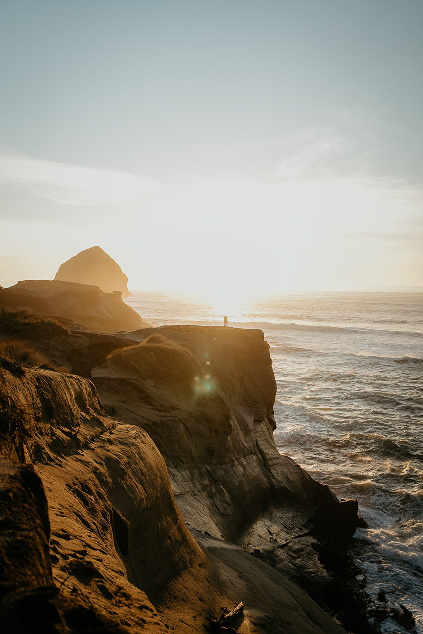 a couple holding each other at sunset with the Oregon coast and a sea stack in the background.