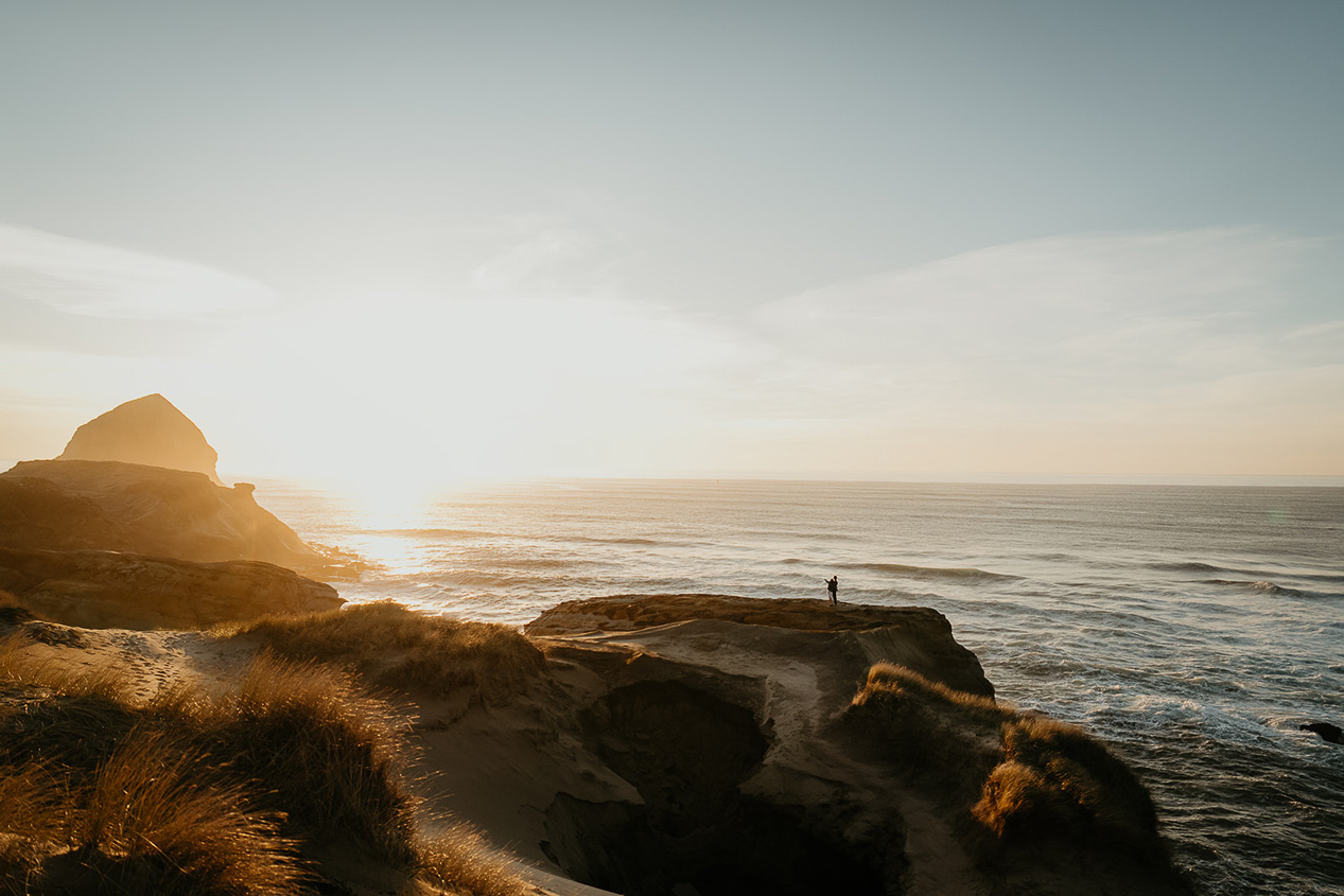 a couple taking in the view of the Oregon coastline at sunset.